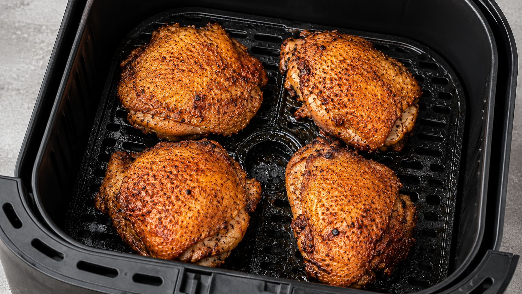Golden brown crispy air fryer chicken thighs seasoned with smoked paprika and garlic, arranged on a white plate with a small bowl of dipping sauce and fresh herbs