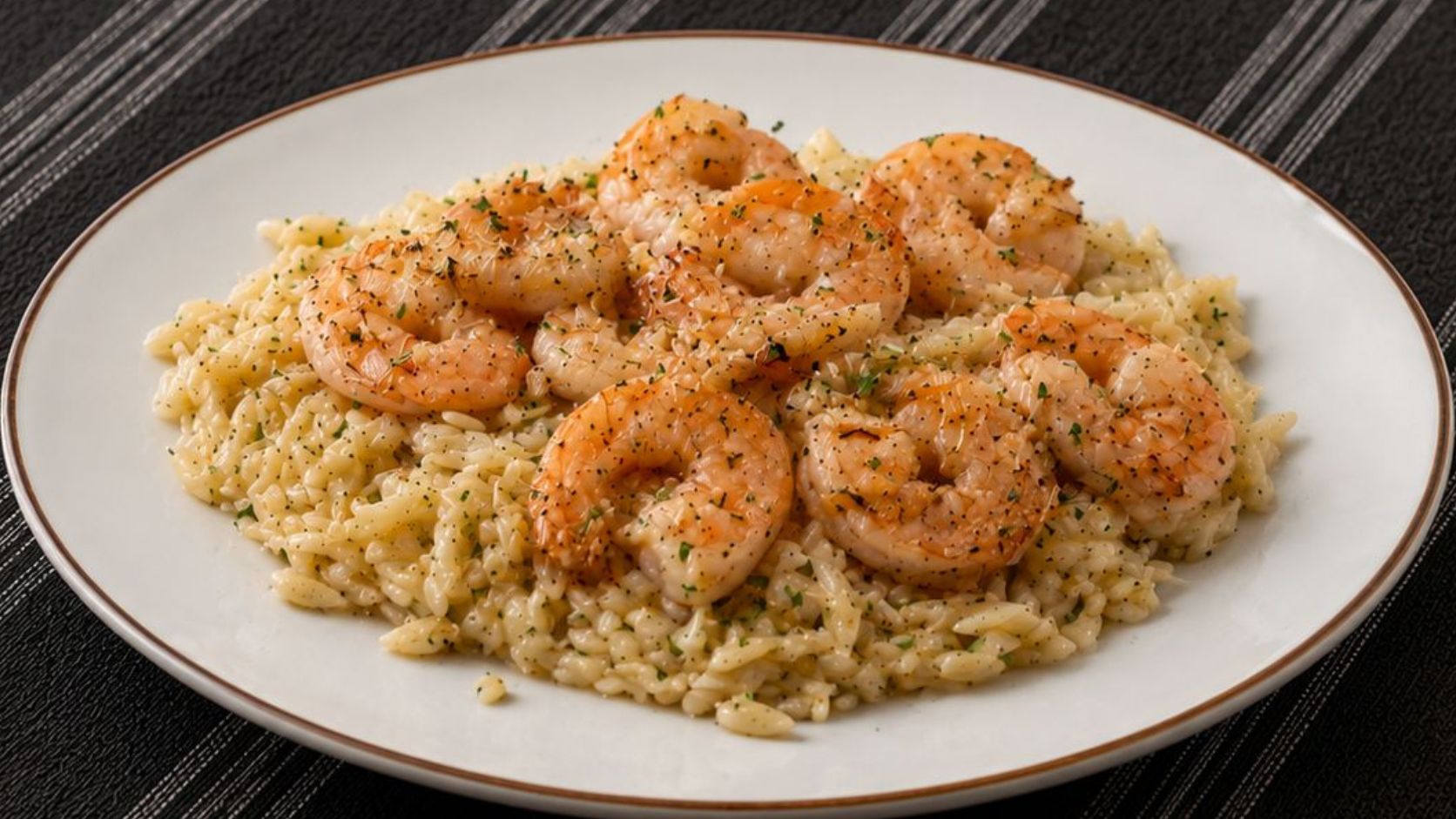 Garlic butter shrimp pasta in a wide white bowl, topped with fresh parsley and Parmesan, with a lemon wedge on the side